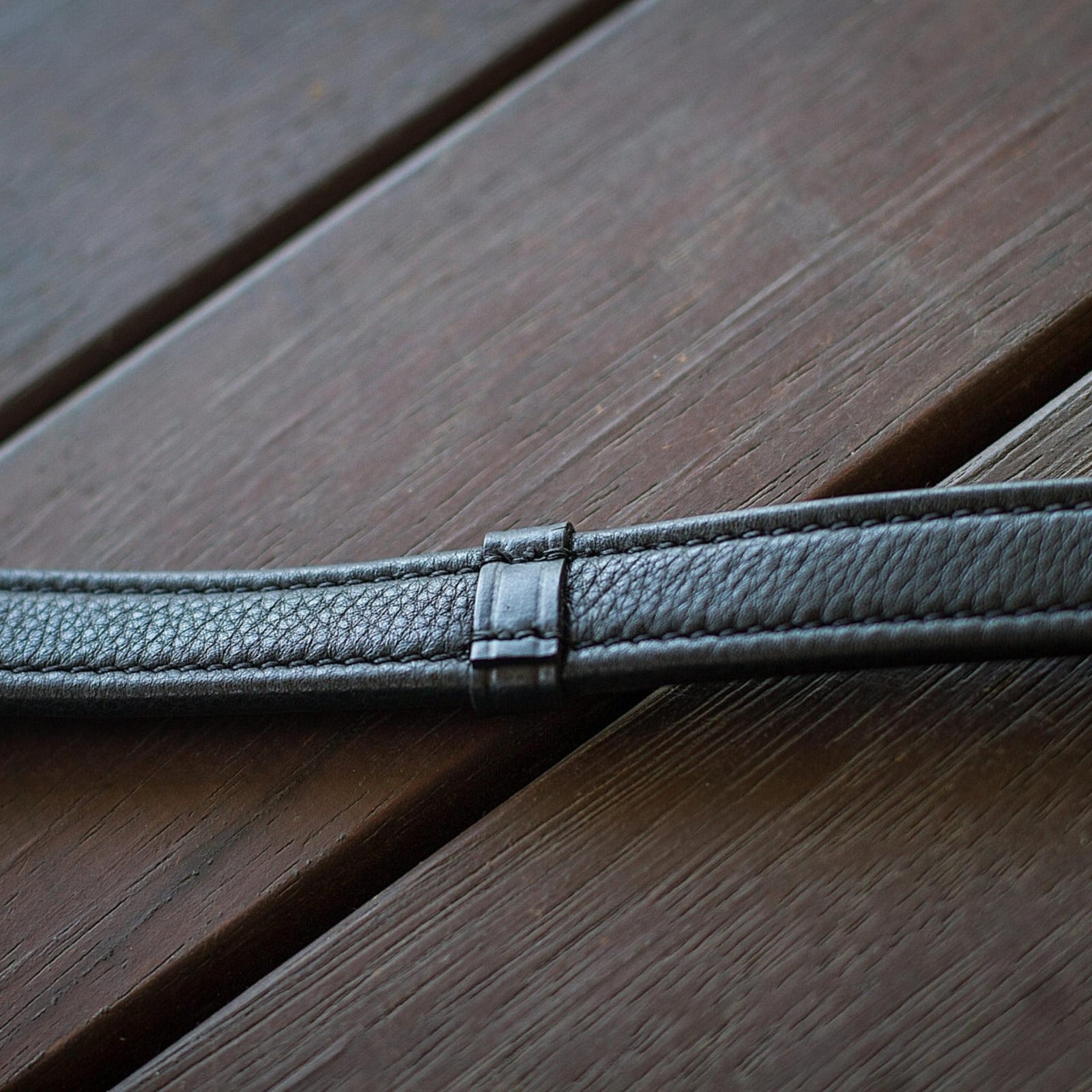 Close up of black leather reins, showing stoppers for rings.