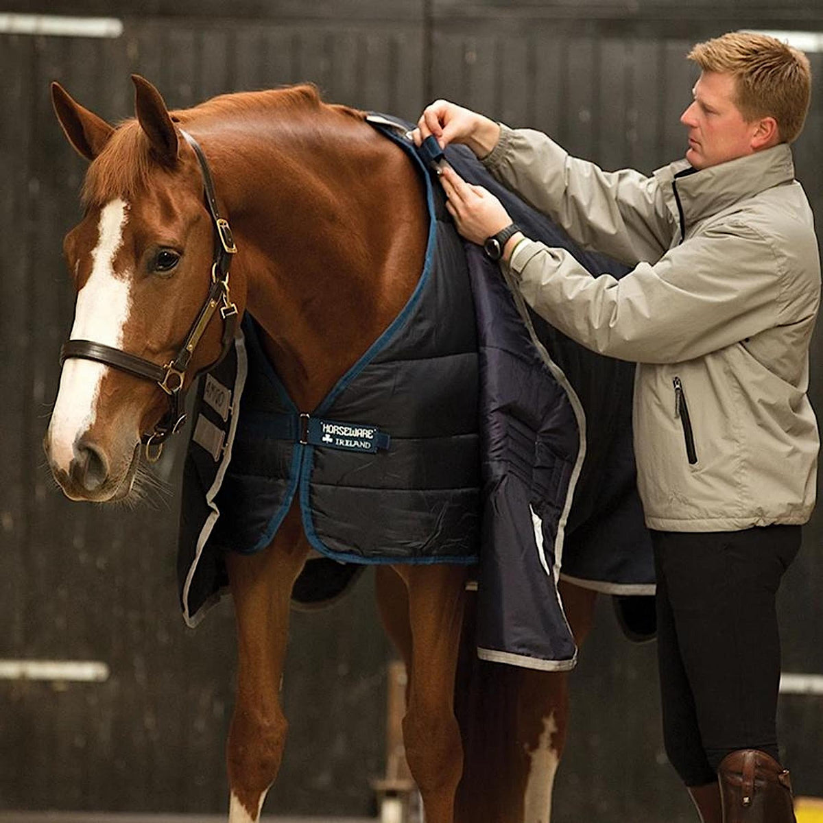 Person fixing horse's liner to top rug with front tabs.